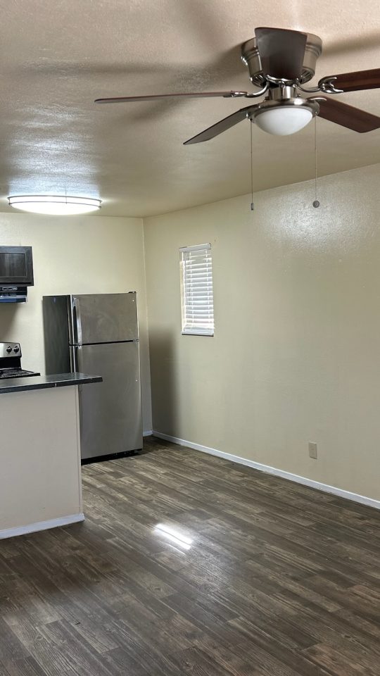 an empty room with a ceiling fan and hardwood floors at The Delmar Place Apartment